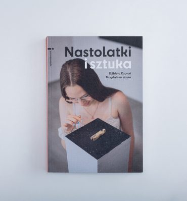 Okładka książki z fotografią młodej, długowłosej dziewczyny przyglądającej się ciekawemu, małemu eksponatowi na postumencie