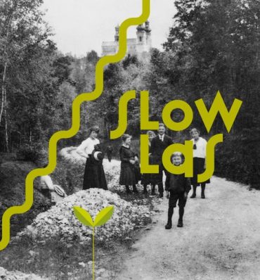 Stara, czarno-biała fotografia z grupą ludzi spacerującą przez las, na zdjęcie nałożony ozdobny, zielony napis "SLOW LAS"