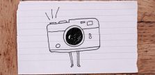 zdjęcie kartki papieru na blacie - na kartce ilustracja aparatu fotograficznego z małymi nóżkami