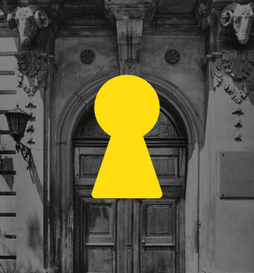 Żółta dziurka od klucza, w tle zdjęcie bramy do pałacu